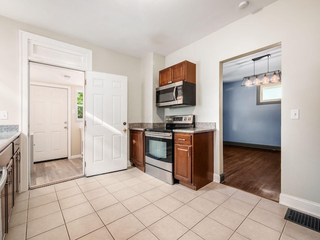 211 E Jenkins Ave, Columbus, OH 43207 - kitchen featuring stainless steel appliances, brown cabinets, light tile patterned floors, and hanging light fixtures