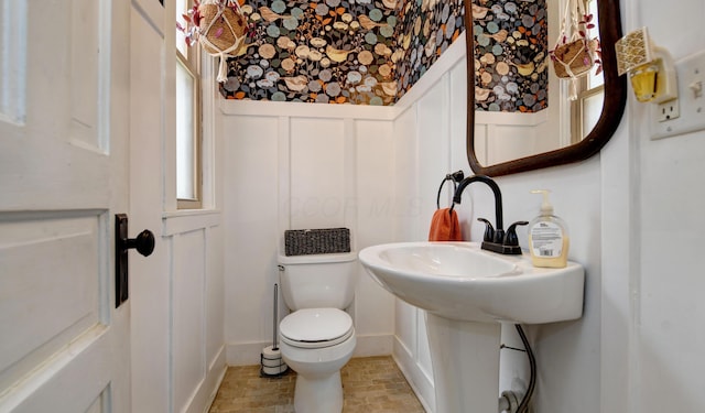 1447 Fair Ave, Columbus, OH 43205 - half bathroom with a decorative wall, wainscoting, stone finish flooring, and wallpapered walls