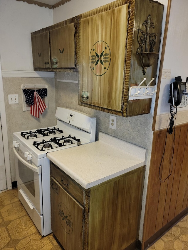327 Ziegler Ave, Columbus, OH 43207 - kitchen with white range with gas cooktop, light countertops, light floors, and brown cabinets