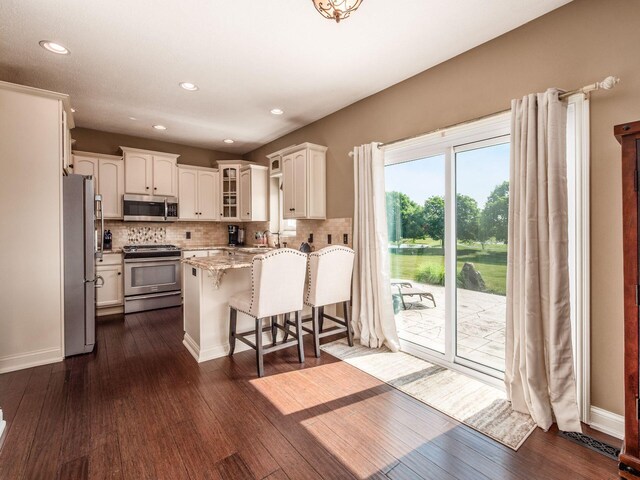 7635 Overland Trl, Delaware, OH 43015 - kitchen featuring stainless steel appliances, a peninsula, tasteful backsplash, light stone counters, and white cabinetry