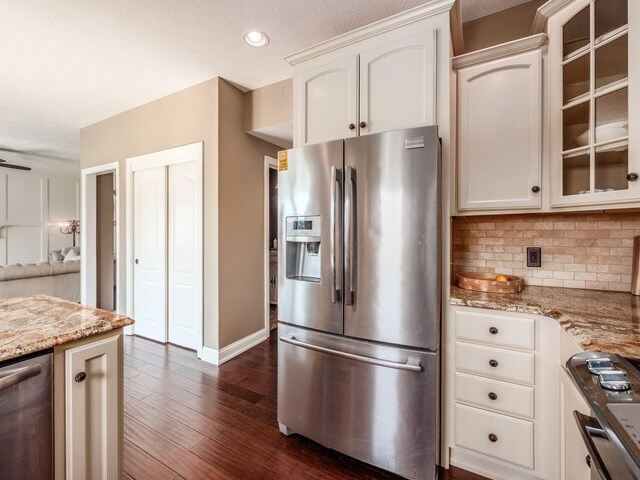 7635 Overland Trl, Delaware, OH 43015 - kitchen featuring stainless steel appliances, backsplash, light stone countertops, dark wood-style flooring, and glass insert cabinets