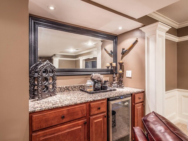 7635 Overland Trl, Delaware, OH 43015 - kitchen with beverage cooler, ornate columns, brown cabinets, crown molding, and light stone countertops