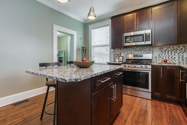 489 Elsmere St, Columbus, OH 43206 - kitchen with stainless steel appliances, a breakfast bar, ornamental molding, dark wood-style floors, and decorative backsplash