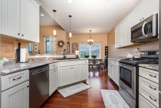 5582 Hayesville Rd, Circleville, OH 43113 - kitchen with stainless steel appliances, a peninsula, a chandelier, dark wood finished floors, and decorative light fixtures