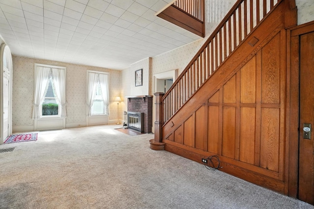 249 W Locust St, Newark, OH 43055 - unfurnished living room with wallpapered walls, carpet flooring, a brick fireplace, and stairway