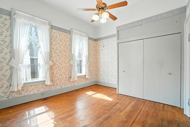 249 W Locust St, Newark, OH 43055 - unfurnished bedroom featuring wood-type flooring, wallpapered walls, a closet, and ceiling fan