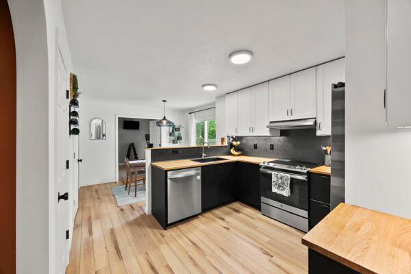 5813 Camhurst Ct, Galloway, OH 43119 - kitchen with stainless steel appliances, butcher block countertops, a peninsula, backsplash, and under cabinet range hood