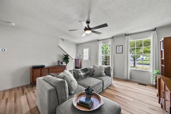 5813 Camhurst Ct, Galloway, OH 43119 - living room with healthy amount of natural light, a ceiling fan, light wood-style floors, and a textured ceiling