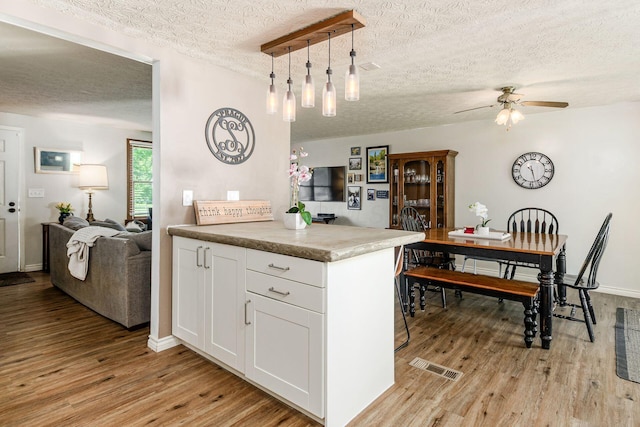 2630 Bella Via Ave, Columbus, OH 43231 - kitchen featuring a textured ceiling, light wood-type flooring, white cabinetry, open floor plan, and a ceiling fan