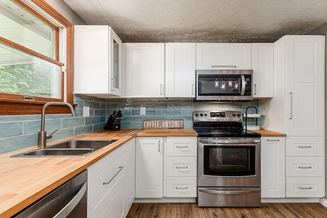 2630 Bella Via Ave, Columbus, OH 43231 - kitchen with appliances with stainless steel finishes, butcher block countertops, decorative backsplash, and white cabinets