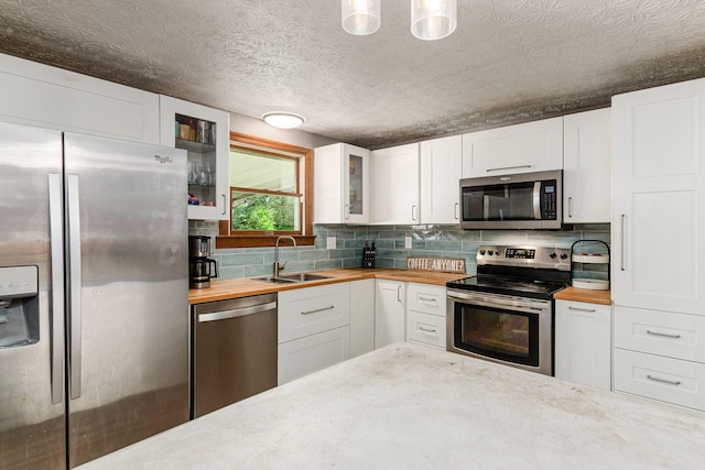 2630 Bella Via Ave, Columbus, OH 43231 - kitchen featuring stainless steel appliances, butcher block counters, glass insert cabinets, backsplash, and white cabinetry