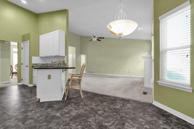 8078 Slate Ridge Blvd, Reynoldsburg, OH 43068 - kitchen featuring dark countertops, ceiling fan, plenty of natural light, white cabinetry, and high vaulted ceiling