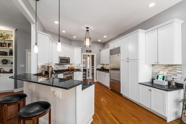 3873 Carters Corner Rd, Sunbury, OH 43074 - kitchen with stainless steel appliances, a peninsula, wood finished floors, tasteful backsplash, and a breakfast bar area