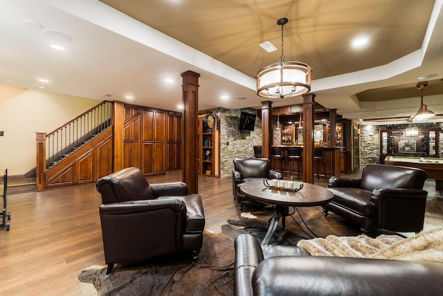 3873 Carters Corner Rd, Sunbury, OH 43074 - living room featuring decorative columns, wood finished floors, stairs, bar, and a raised ceiling