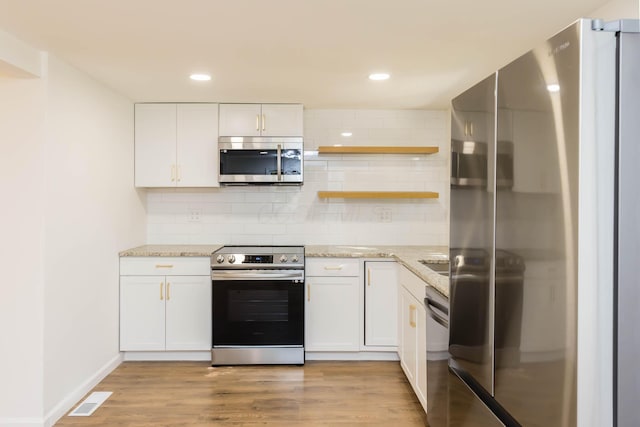 1718 S 3rd St, Columbus, OH 43207 - kitchen with appliances with stainless steel finishes, white cabinetry, backsplash, light wood-style flooring, and light stone countertops