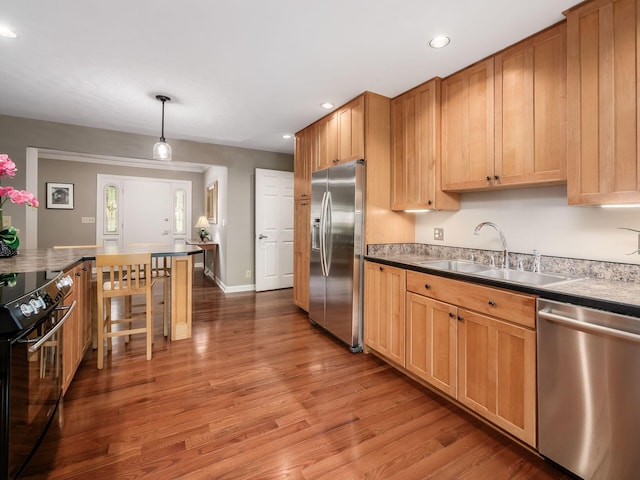 4656 Crompton Dr, Columbus, OH 43220 - kitchen featuring appliances with stainless steel finishes, wood finished floors, recessed lighting, pendant lighting, and a breakfast bar