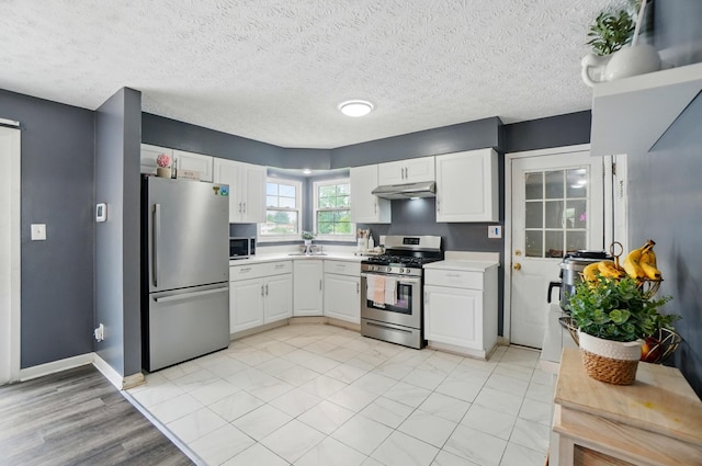 3722 Florian Dr, Columbus, OH 43219 - kitchen with stainless steel appliances, under cabinet range hood, light countertops, white cabinetry, and a textured ceiling