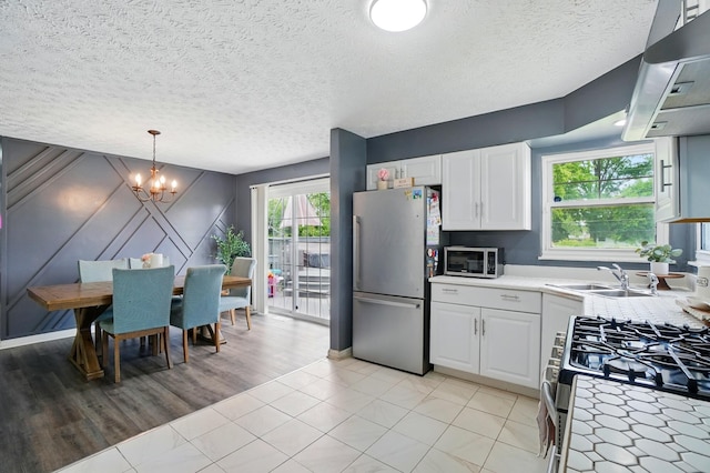 3722 Florian Dr, Columbus, OH 43219 - kitchen with stainless steel appliances, a chandelier, light countertops, extractor fan, and white cabinetry