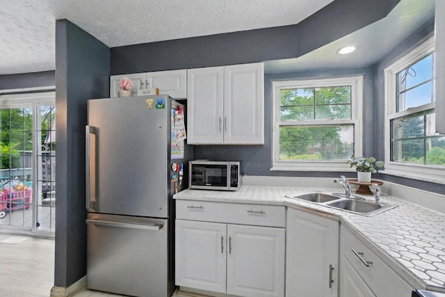 3722 Florian Dr, Columbus, OH 43219 - kitchen featuring appliances with stainless steel finishes, white cabinets, healthy amount of natural light, light countertops, and a textured ceiling