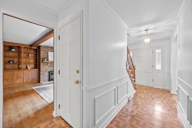 1295 Castleton Rd N, Columbus, OH 43220 - foyer entrance featuring a fireplace, a decorative wall, stairs, ornamental molding, and parquet floors