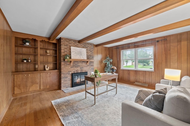 1295 Castleton Rd N, Columbus, OH 43220 - living room featuring light wood finished floors, beam ceiling, a fireplace, and wooden walls