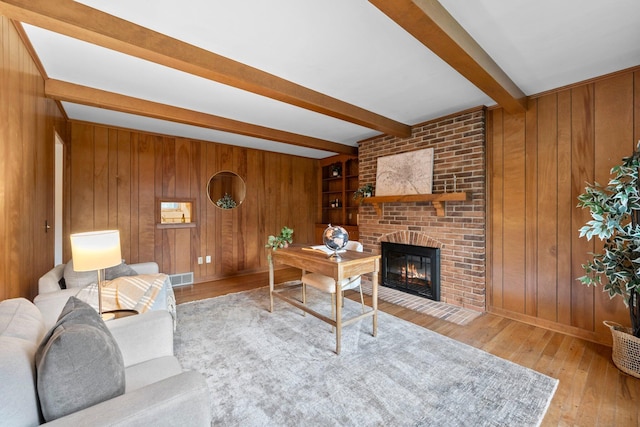 1295 Castleton Rd N, Columbus, OH 43220 - living room featuring beam ceiling, wood walls, wood-type flooring, and a brick fireplace
