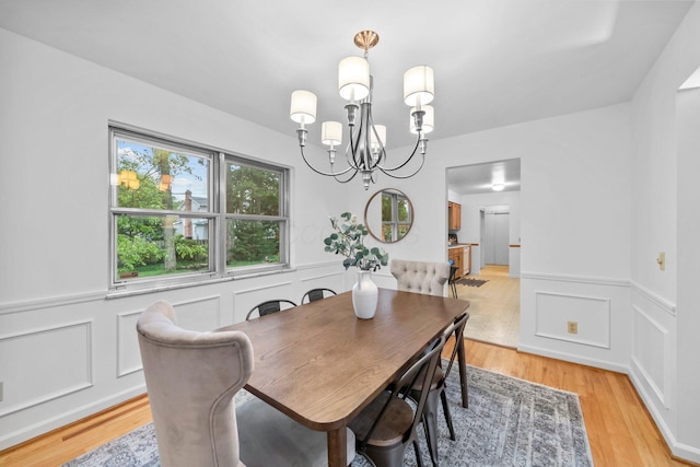 1295 Castleton Rd N, Columbus, OH 43220 - dining space with a chandelier, a wainscoted wall, light wood-style floors, and a decorative wall