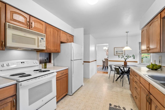 1295 Castleton Rd N, Columbus, OH 43220 - kitchen featuring white appliances, light countertops, hanging light fixtures, and brown cabinetry
