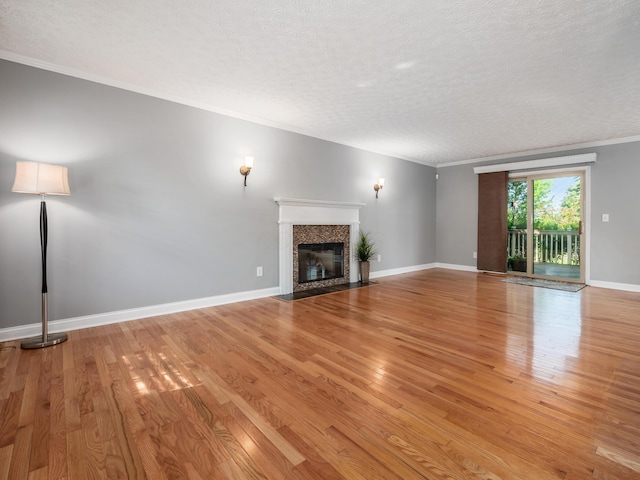 304 Cottage Grove Cir, Pataskala, OH 43062 - unfurnished living room with a textured ceiling, light wood-type flooring, a tile fireplace, and crown molding