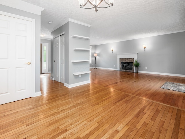 304 Cottage Grove Cir, Pataskala, OH 43062 - unfurnished living room with a textured ceiling, light wood-style flooring, a tile fireplace, a chandelier, and crown molding