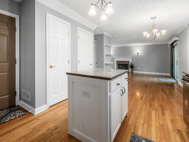304 Cottage Grove Cir, Pataskala, OH 43062 - kitchen with a chandelier, light wood-style floors, open floor plan, white cabinets, and a textured ceiling