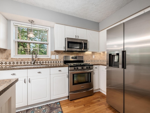 304 Cottage Grove Cir, Pataskala, OH 43062 - kitchen featuring appliances with stainless steel finishes, dark countertops, light wood-style flooring, white cabinetry, and decorative backsplash