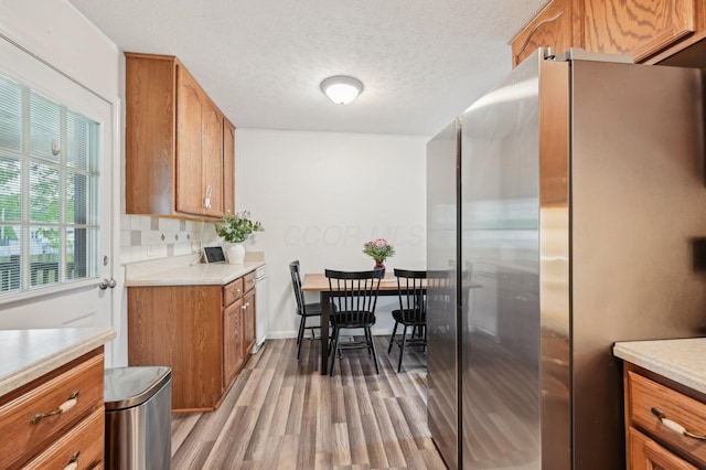 1853 Shasta Dr, Lancaster, OH 43130 - kitchen featuring stainless steel fridge with ice dispenser, brown cabinets, wood finished floors, light countertops, and a textured ceiling