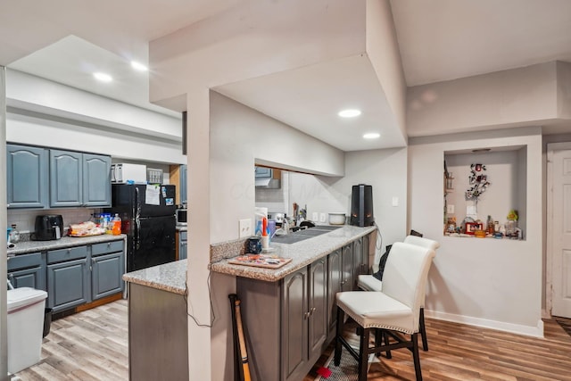 137 Wisconsin Ave, Columbus, OH 43222 - kitchen featuring freestanding refrigerator, light wood-type flooring, recessed lighting, tasteful backsplash, and a kitchen bar