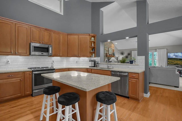 15 Doe St, Plain City, OH 43064 - kitchen featuring appliances with stainless steel finishes, a kitchen bar, light wood-type flooring, open floor plan, and high vaulted ceiling
