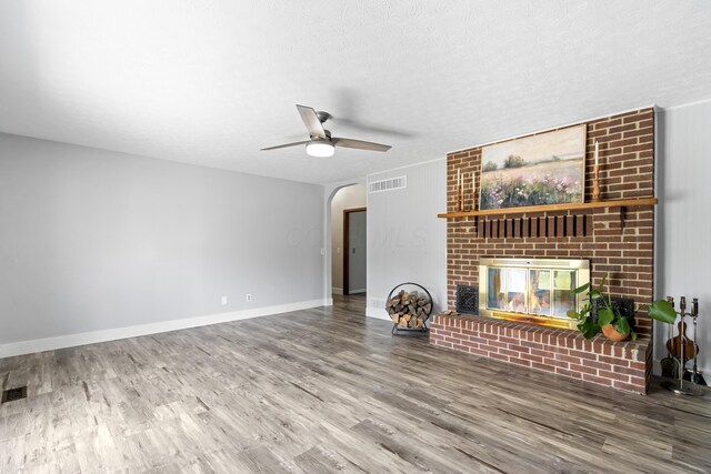1550 Hiner Rd, Orient, OH 43146 - unfurnished living room with a brick fireplace, wood finished floors, a ceiling fan, arched walkways, and a textured ceiling
