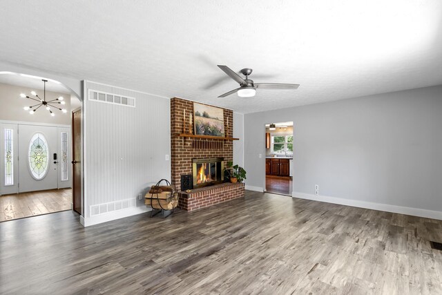 1550 Hiner Rd, Orient, OH 43146 - unfurnished living room featuring wood finished floors, a brick fireplace, ceiling fan, a chandelier, and arched walkways