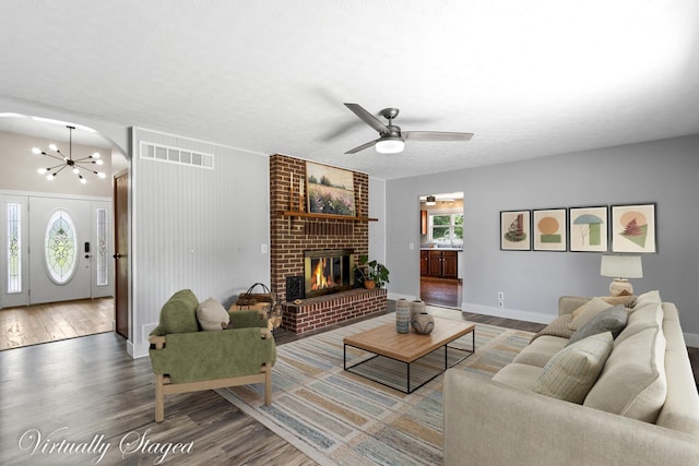 1550 Hiner Rd, Orient, OH 43146 - living area featuring wood finished floors, a brick fireplace, a ceiling fan, a chandelier, and arched walkways