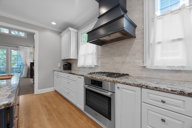 1359 White Oak Ln, New Albany, OH 43054 - kitchen with appliances with stainless steel finishes, custom range hood, ornamental molding, white cabinetry, and light wood finished floors