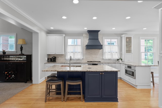 1359 White Oak Ln, New Albany, OH 43054 - kitchen featuring custom range hood, a breakfast bar, white cabinetry, plenty of natural light, and crown molding
