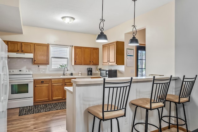 861 Summerville Dr, Delaware, OH 43015 - kitchen with electric range, under cabinet range hood, light wood-style flooring, a breakfast bar area, and light countertops