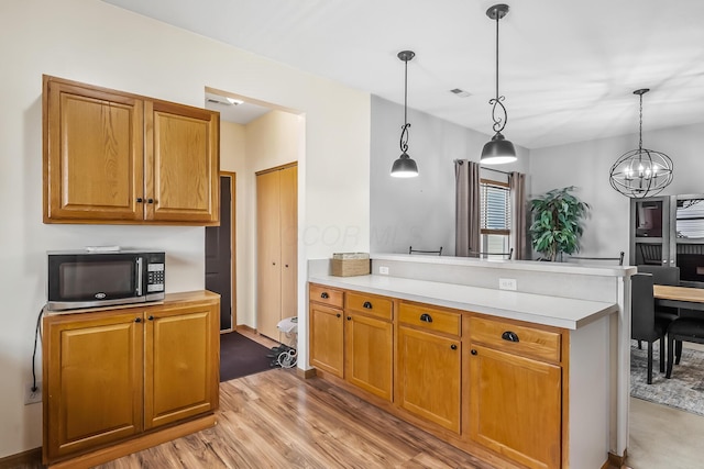 861 Summerville Dr, Delaware, OH 43015 - kitchen with a peninsula, a chandelier, light wood finished floors, and light countertops