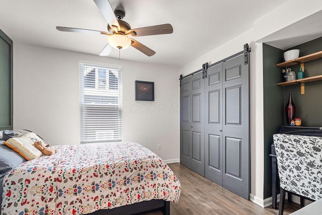 112 Oak Hill Ave, Delaware, OH 43015 - bedroom featuring a barn door, wood finished floors, a ceiling fan, and a closet
