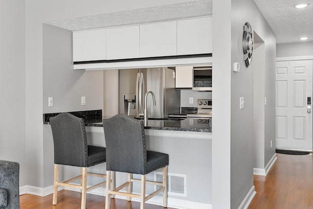1814 Bennigan Dr Unit 88B, Hilliard, OH 43026 - kitchen with appliances with stainless steel finishes, wood finished floors, dark stone countertops, white cabinets, and recessed lighting