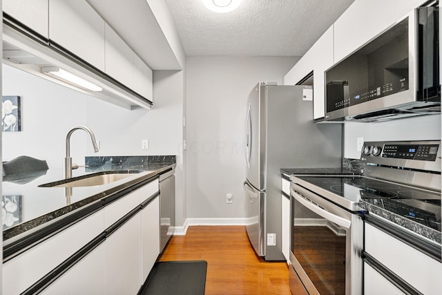 1814 Bennigan Dr Unit 88B, Hilliard, OH 43026 - kitchen featuring appliances with stainless steel finishes, white cabinetry, light wood-type flooring, a textured ceiling, and dark stone counters