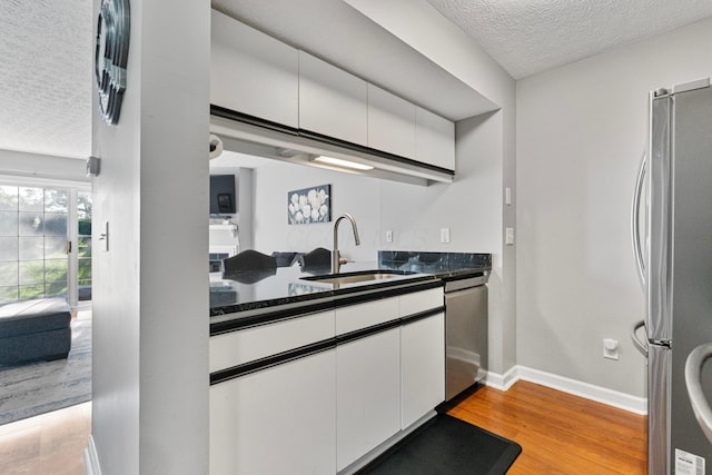 1814 Bennigan Dr Unit 88B, Hilliard, OH 43026 - kitchen featuring appliances with stainless steel finishes, a textured ceiling, white cabinetry, and light wood-style floors