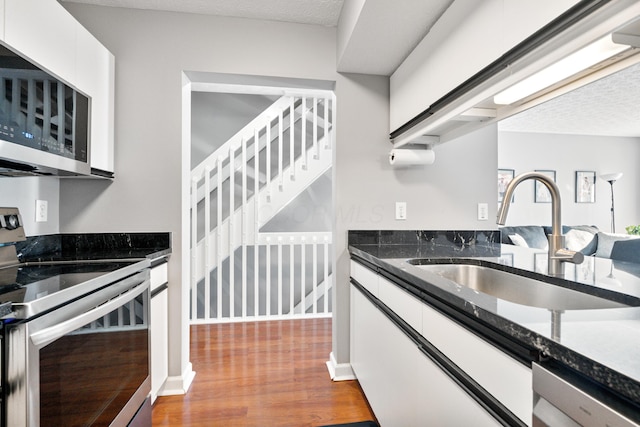 1814 Bennigan Dr Unit 88B, Hilliard, OH 43026 - kitchen featuring appliances with stainless steel finishes, wood finished floors, white cabinets, dark stone countertops, and a textured ceiling