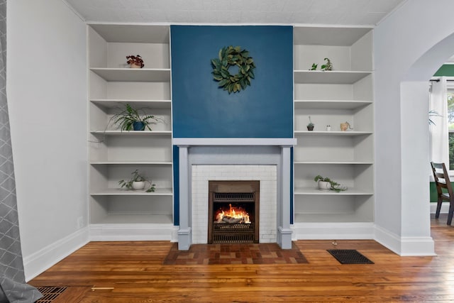 116 W Longview Ave, Columbus, OH 43202 - unfurnished living room with arched walkways, wood finished floors, built in shelves, and a fireplace