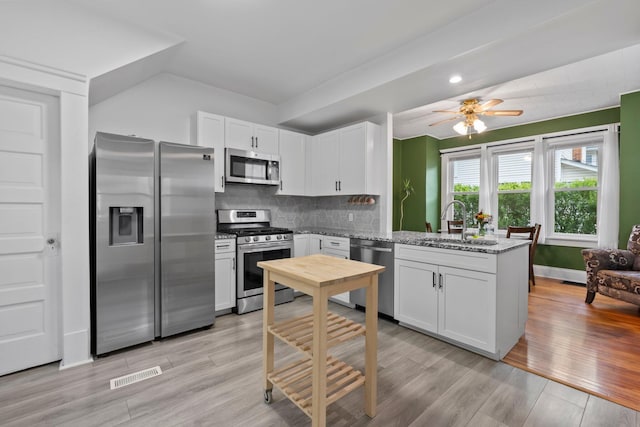 116 W Longview Ave, Columbus, OH 43202 - kitchen with appliances with stainless steel finishes, a peninsula, ceiling fan, white cabinetry, and light wood finished floors
