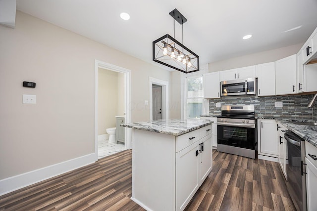 765 Campbell Ave, Columbus, OH 43222 - kitchen with stainless steel appliances, tasteful backsplash, a kitchen island, dark wood-type flooring, and light stone counters